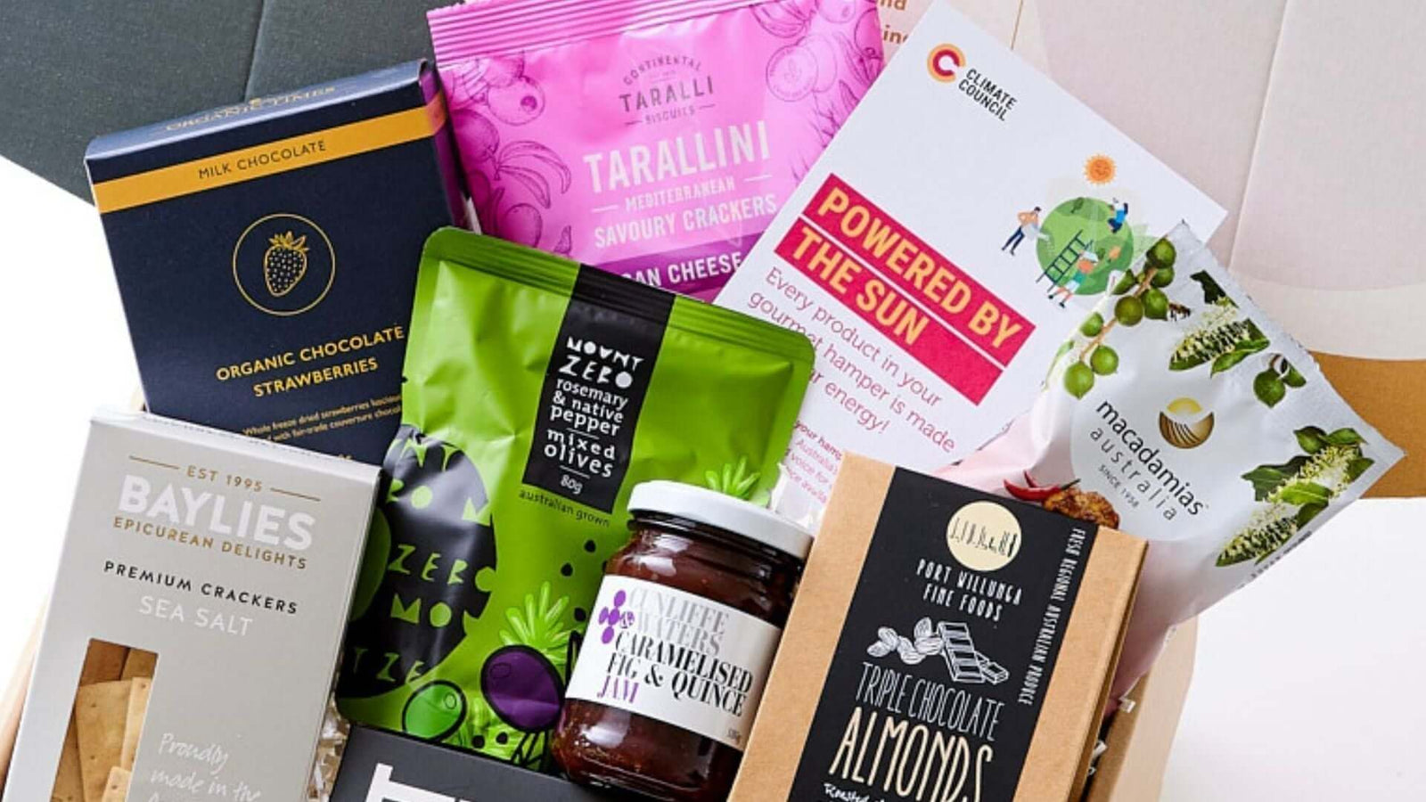 a hamper filled with assorted gourmet treats, including chocolate bars, nuts, dried fruits, snack packs, and premium spreads, neatly arranged in a box for gifting