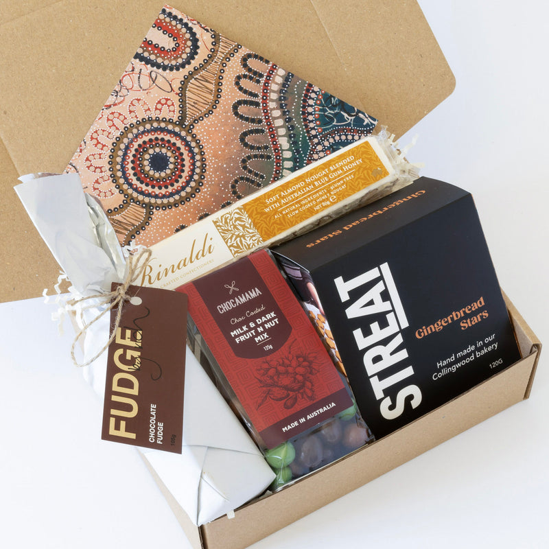 A gift box with local handmade treats including gingerbread stars, salted caramel fudge, almond nougat, and a fruit and nut mix from curated with conscience