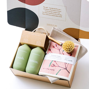 A hamper with natural hand wash and lotion, organic cotton towel, compostable sponges, and a sustainable bamboo dish brush — a stylish, eco-friendly home gift.