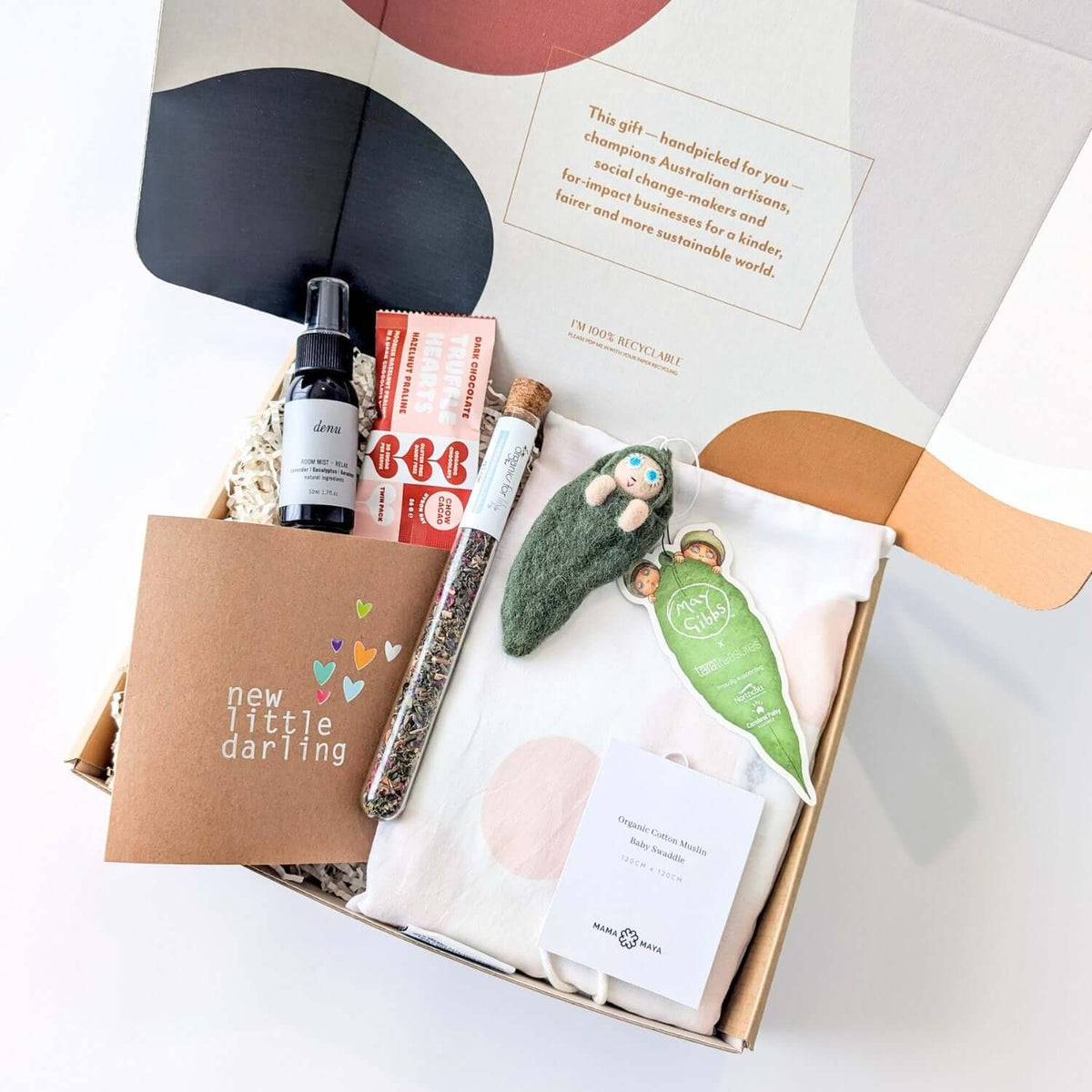 Gift box with various items including a bottle, book, and decorative elements on a white background from curated with conscience, perfect for a thoughtful gift