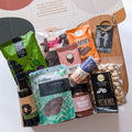 Gourmet gift basket with various food items on a white background from curated with conscience, perfect treats as a gift