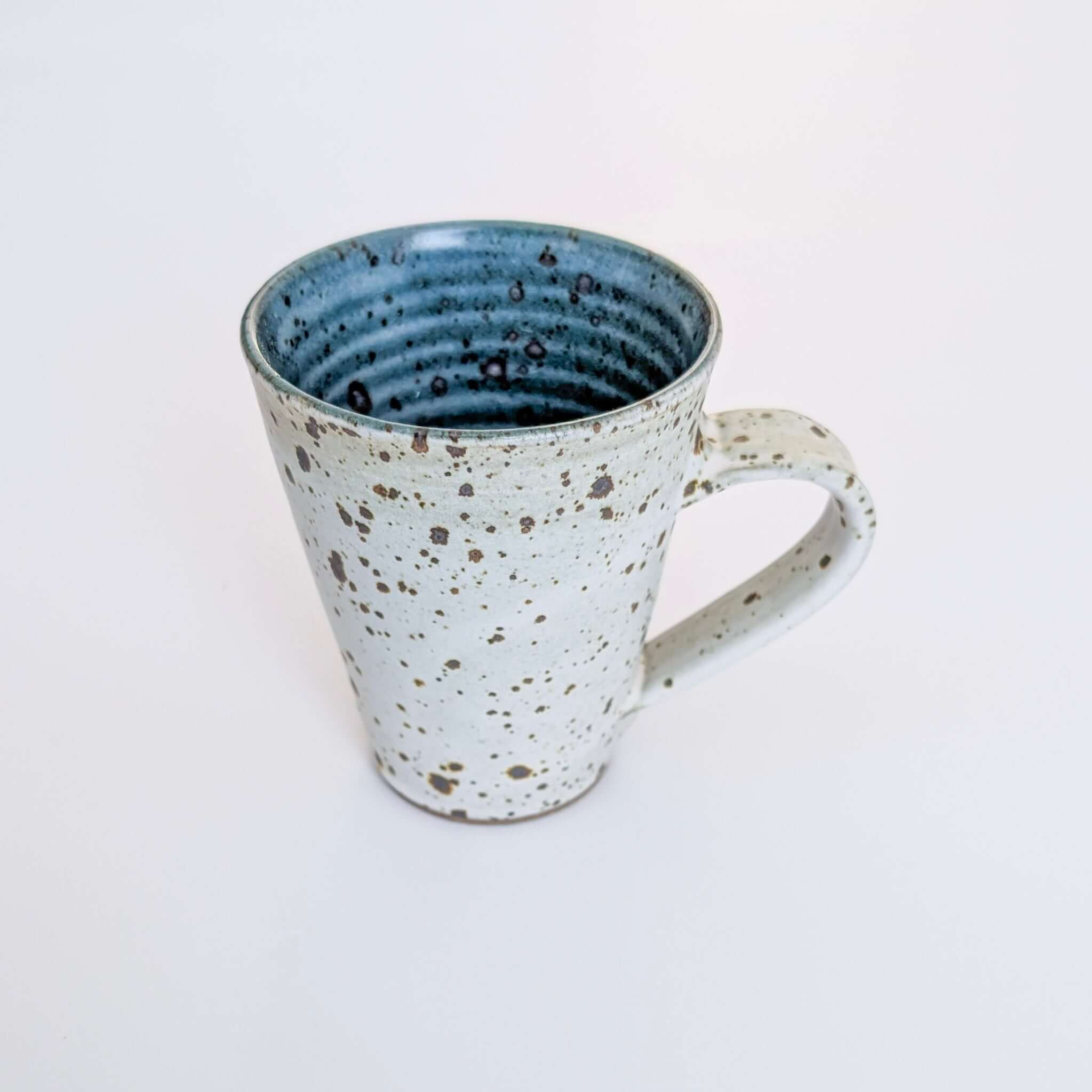Handcrafted ceramic cup with speckled exterior and azure interior by John Gleeson, made in Central Victoria included in the hamper by curated with conscience