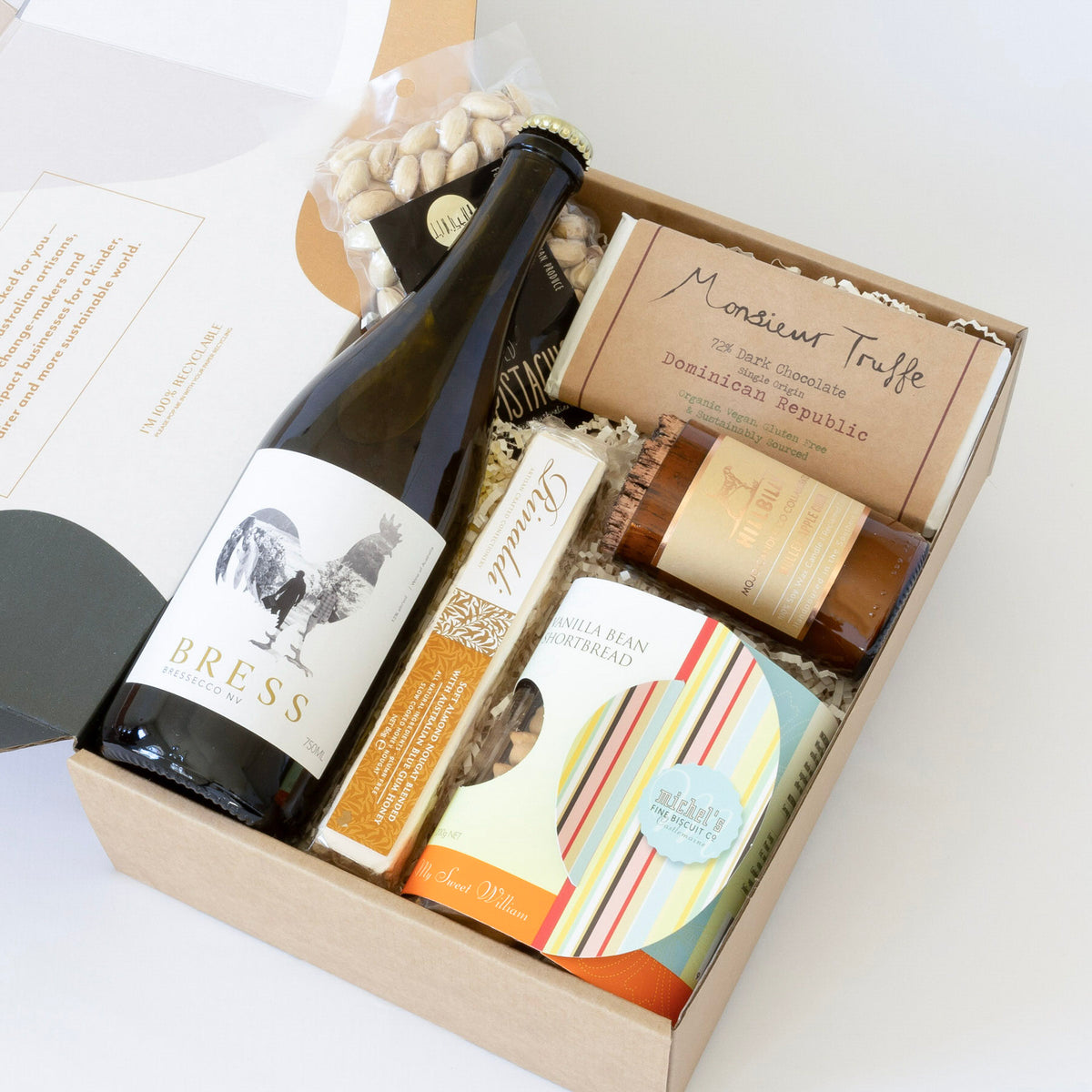A gift box with Bress &#39;Bressecco&#39; sparkling wine, mulled apple cider-scented soy candle, dark chocolate, vanilla bean shortbread, almond nougat, and Australian pistachios. Featuring handcrafted, locally sourced artisan goods.