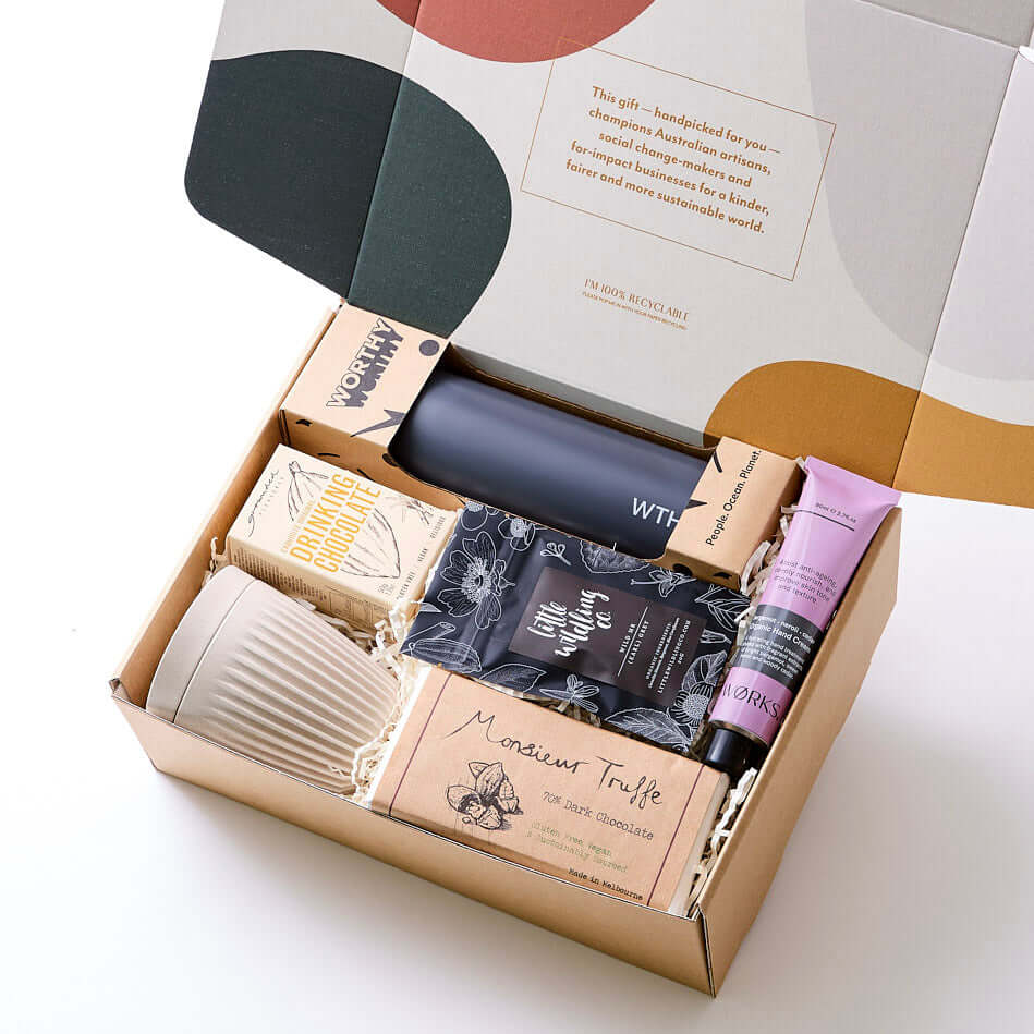 A hamper with sustainable sugar cane water bottle, repurposed coffee husk cup, organic dark chocolate, Earl Grey tea, vegan drinking chocolate, and bergamot hand cream. A stylish eco-friendly gift to start the workday right.