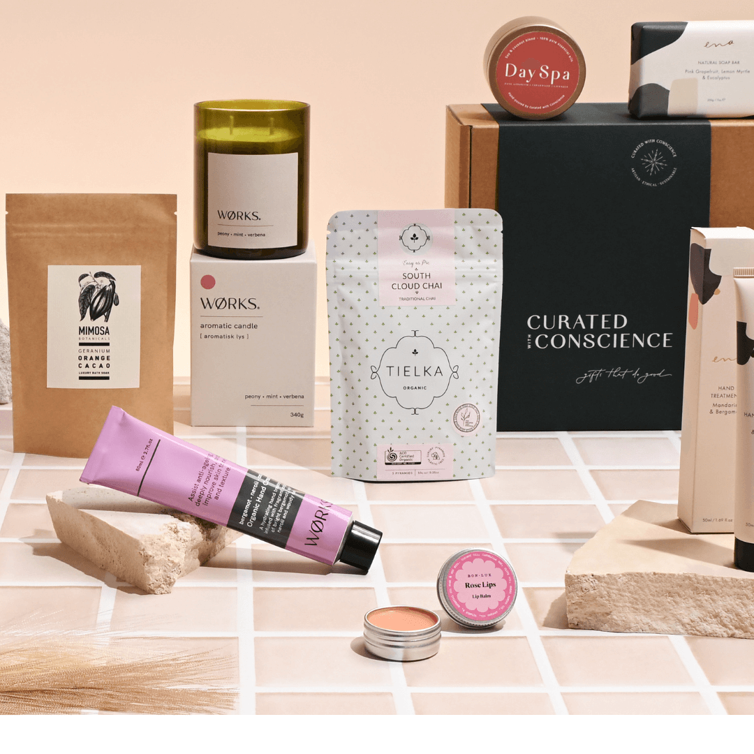 premium vegan hampers featuring natural skincare, tea, candle, and eco-conscious self-care products from Curated with Conscience, beautifully arranged on a tiled surface with minimalist packaging
