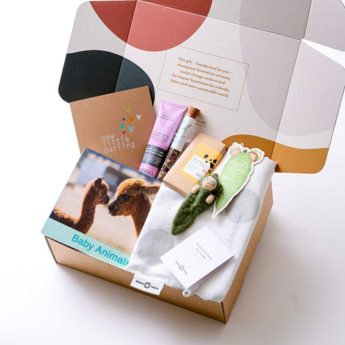 A hamper with organic cotton wrap, handcrafted baby ornament, baby animal book, plastic-free hand cream, herbal glow tea, vegan chocolate, and a recycled gift card -nurturing baby and mama.