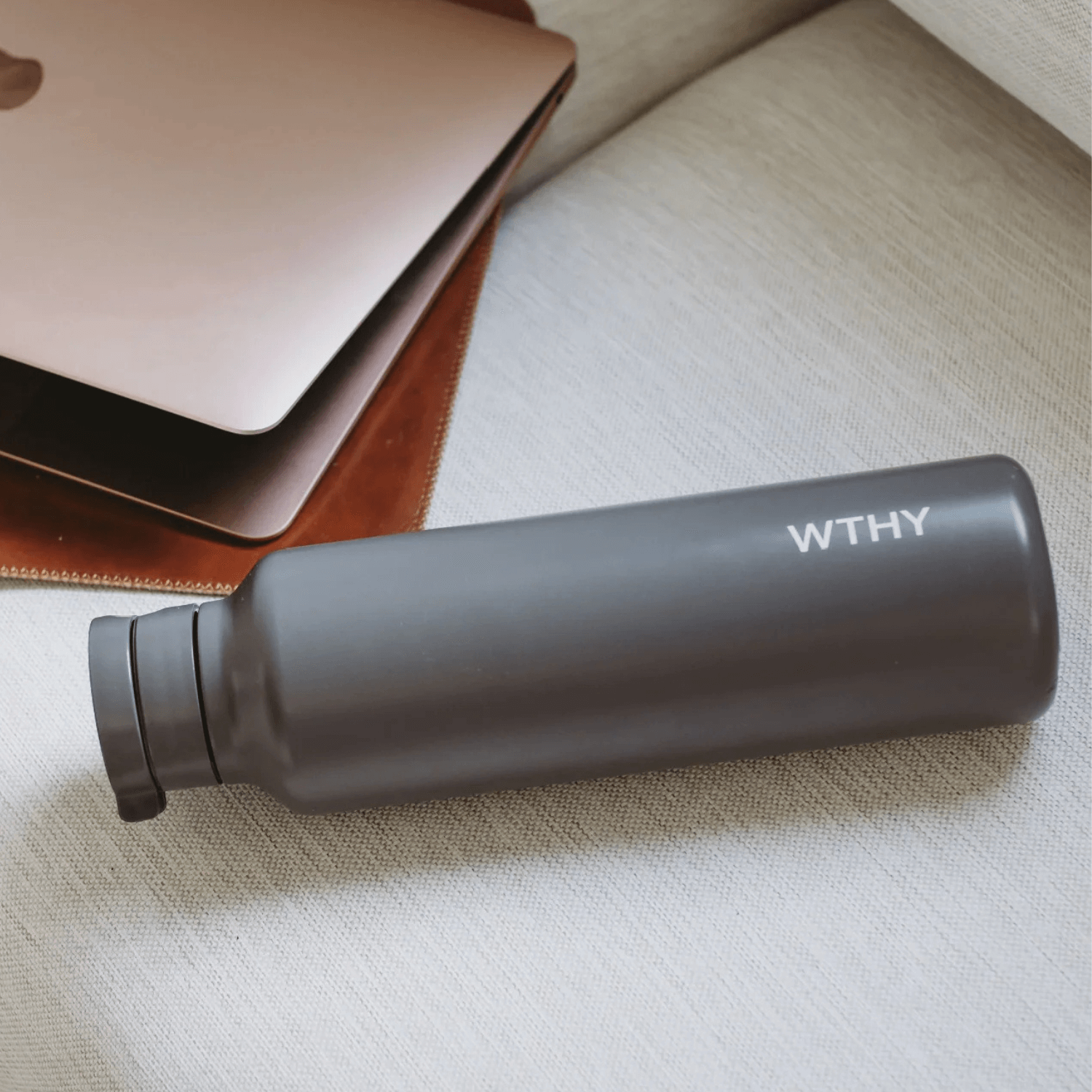 Black water bottle with 'WTHY' branding on a textured surface included in the hamper of curated with conscience