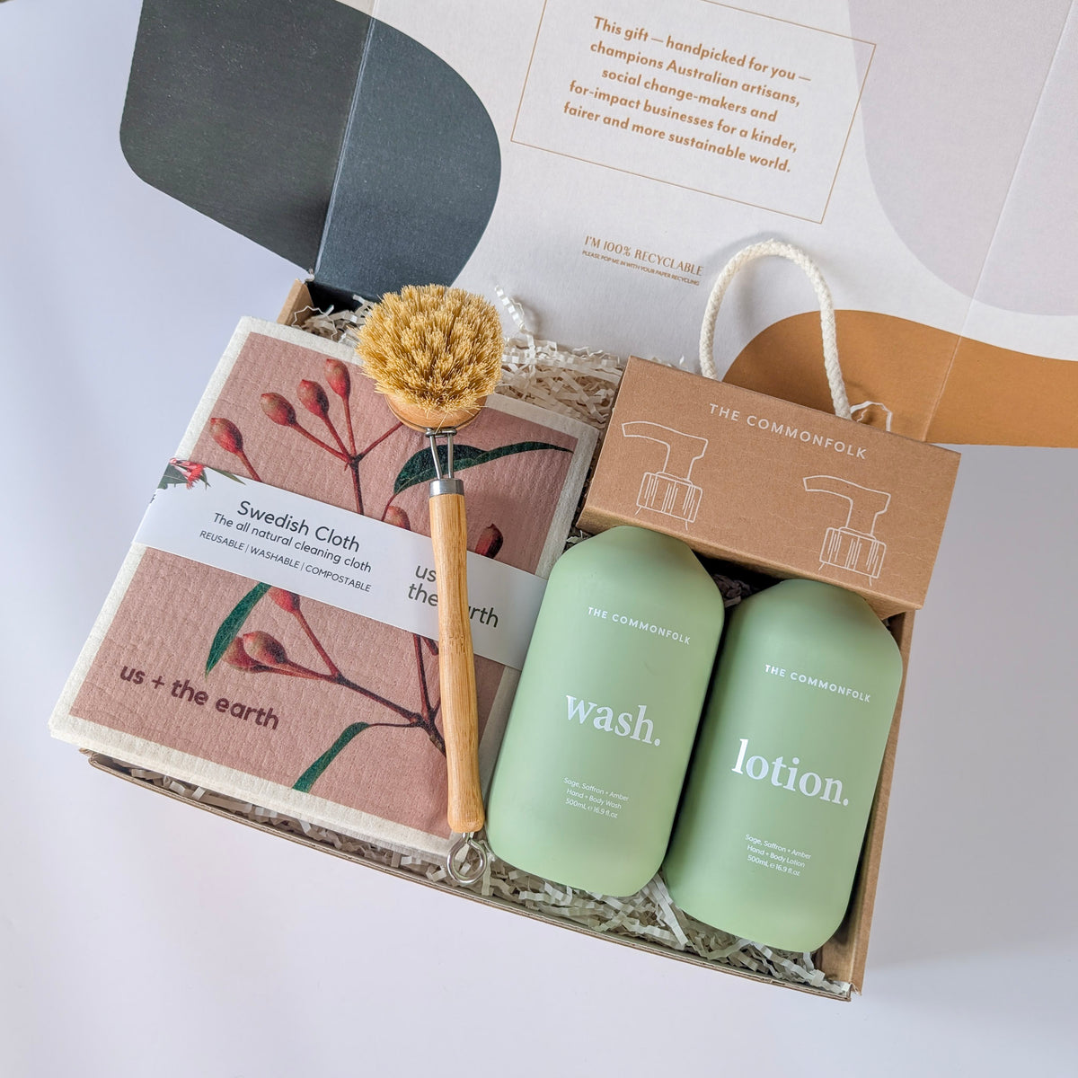 Gift set with two green bottles labeled &#39;wash&#39; and &#39;lotion&#39;, a Swedish cloth, and a brush on a white background from curated with conscience, perfect for travel gifts